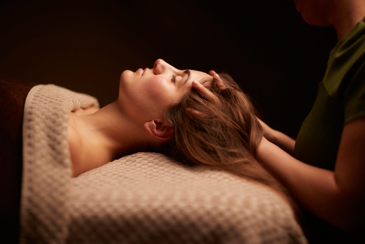 Spa therapist giving a woman a relaxing scalp massage.